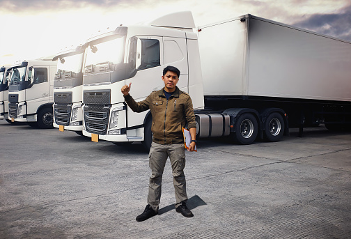 Truck Drivers Standing and Thumb-Up. Semi Trailer Trucks on The Parking Lot. Checking the Truck's Safety of Maintenance. Freight Truck Logistics