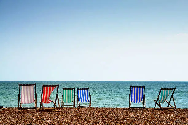 Colourful striped deckchairs on the shingle beach at Brighton, East Sussex, on a summer day