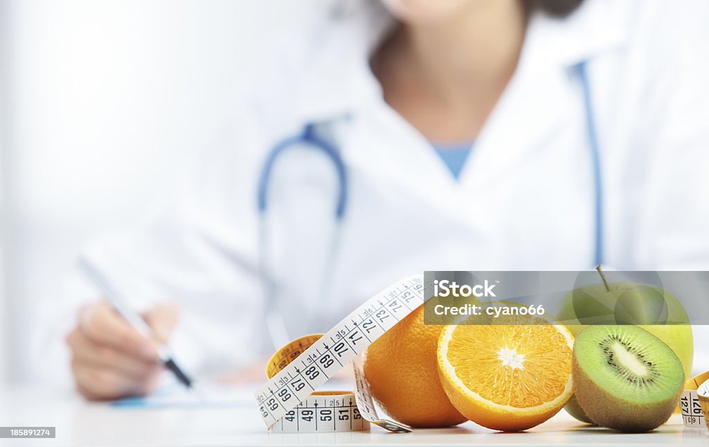 Diet Nutritionist Doctor is writing a prescription. Focus on fruit Nutritionist Stock Photo