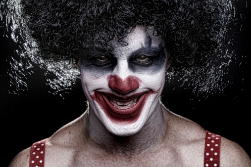 Mid adult man in prisoner costume with red hair and red contact lens imitating a scary  clown for a Halloween event