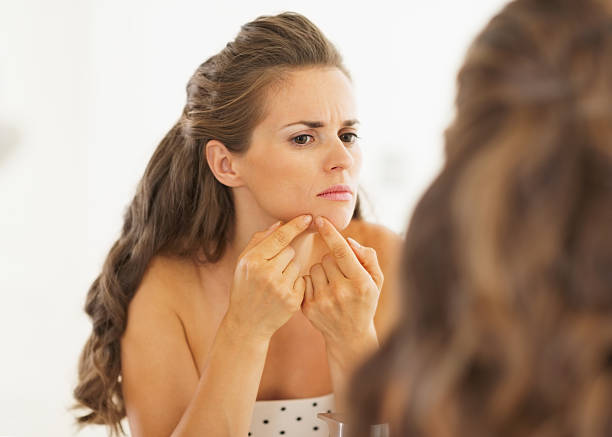 istock Young woman squeezing acne in bathroom 185897732