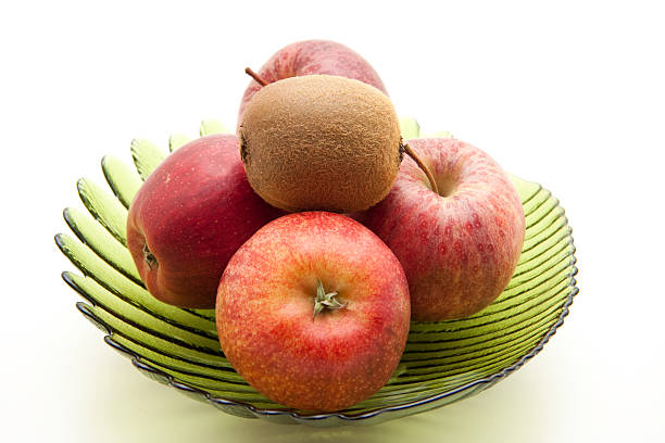 Apples and kiwi and glass bowl and on white background