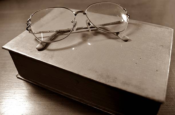 istock Glasses on the old book sepia 185898710