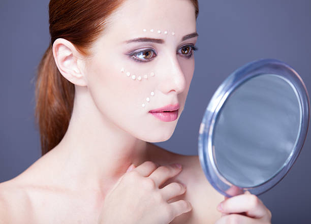 istock women with cosmetic cream on a chee 185900812