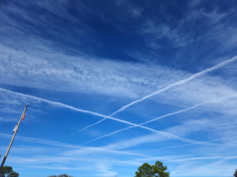 Multiple Jet Contrails Crossing In Blue Skies