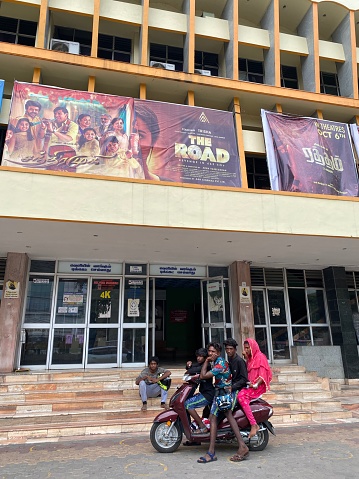 Coimbatore, Tamil Nadu, India - October 10 2023: A group of young Indian people on a bike outside a single screen movie theater.