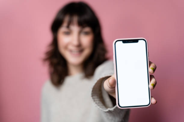 istock Woman showing a smartphone with a white screen on a pink background. 1859045421