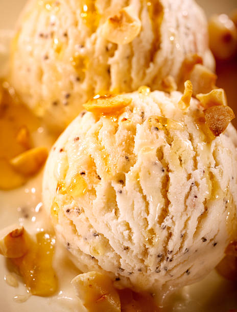 Close-up of a woman hand holding a waffle cone filled with creamy vanilla ice cream and a plastic spoon in a bright indoor setting.