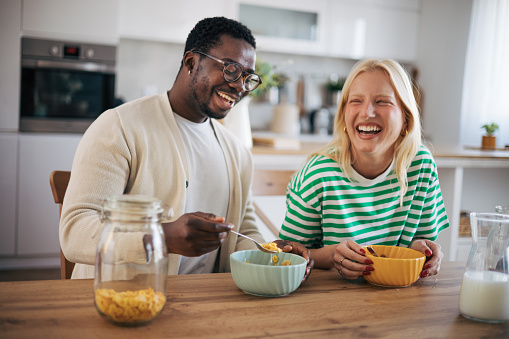 Young happy couple (albino and afro man) having breakfast at home