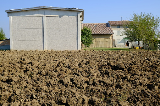 Farmhouse in the Italian countryside. Plowed land and old country house with prefab building.  Stock photos. Busseto, Parma, Italy.