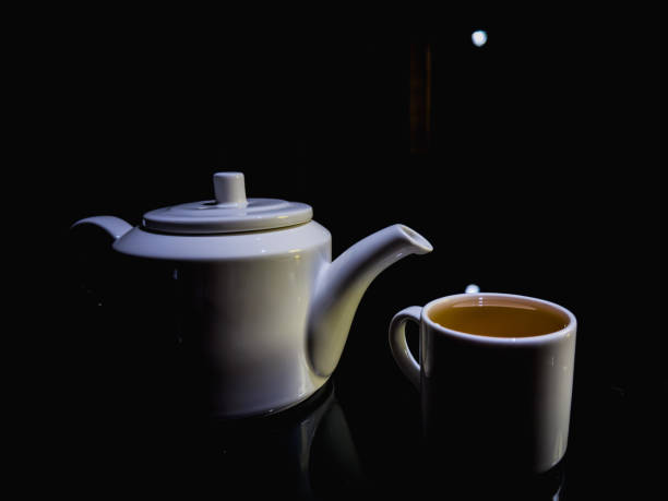 Restaurant, white teapot, white tea cup with tea, tea ceremony. Dark background