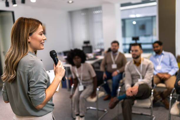 istock Young bussines woman lecturing her multiethnic colleagues. Having a speach while holding a microphone. 1859134666
