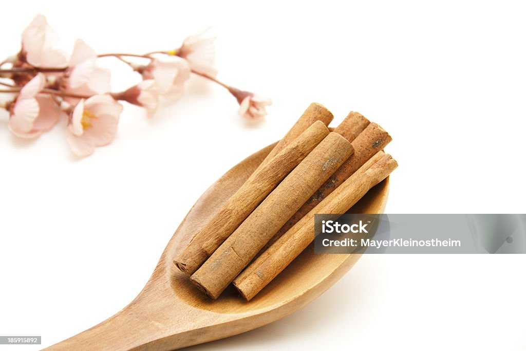 Cinnamon sticks on wooden spoon Cinnamon sticks on wooden spoon and flowering branch on white background Brown Stock Photo