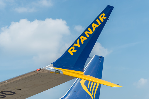Ferno, Milan-Malpensa, Italy - October 3, 2023: View of the Ryanair plane wing with yellow and blue logo in the Milan-Malpensa international airport.