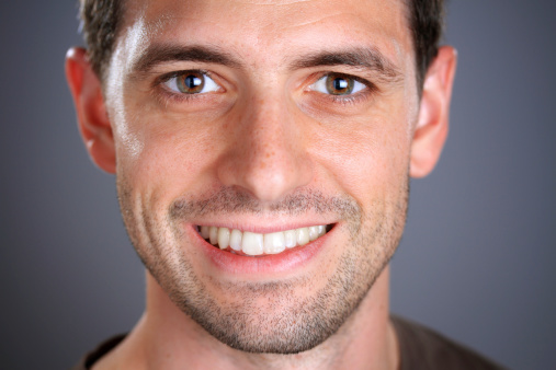 Portrait of a real smiling man looking at camera. Extreme Closeup