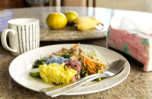 Thai traditional healthy food, Khao Yam on the table, Three colored rice with vegetables, herbs, fish meal, lemon and seasoning sauce