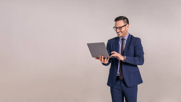 istock Smiling handsome professional in glasses working over laptop while standing on white background 1859234537