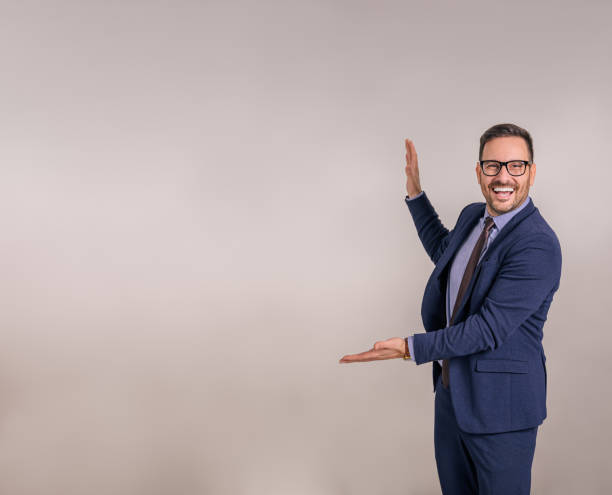 happy young salesman laughing and presenting new product while standing against white background - boegbeeld model stockfoto's en -beelden