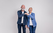 Portrait of happy senior couple screaming and giving fist bumps while standing on white background