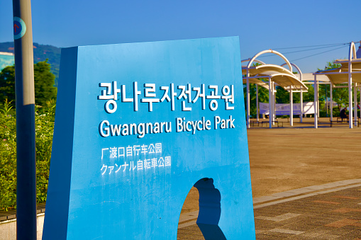 Seoul, South Korea - June 2, 2023: The iconic blue sign of Gwangnaru Bicycle Park, prominently displayed with the park's courtyard visible in the background.