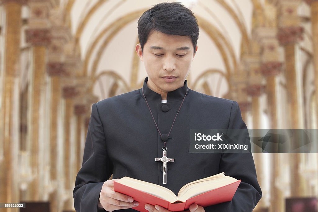Priest Looking at Bible in a Church Priest Stock Photo