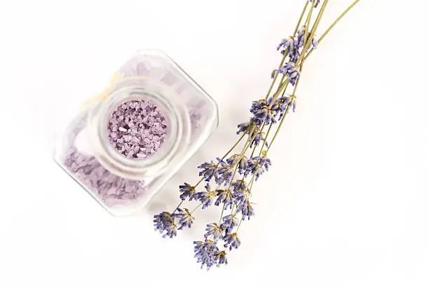 Dry lavender and glass with lavender salt on white background