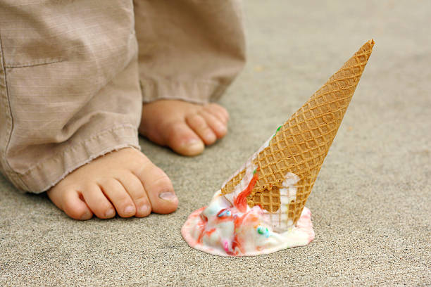 Young child drops their ice cream cone by their feet stock photo