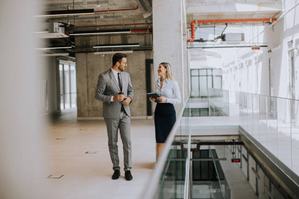 istock Young coworkers walking and talking along corridor in modern office 1859266149