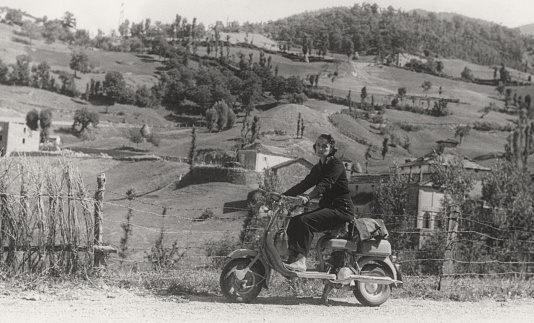 Young Woman on Vintage Motor Scooter in a country road. 1952. Sepia Toned.