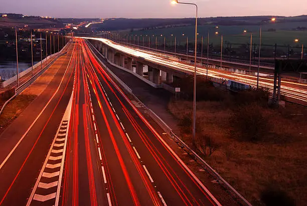 Trails of light left by vehicles travelling at night on a motorway in England UK