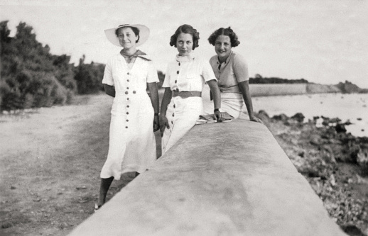 Group of young women smiling close to the sea. 1930. Sepia Toned.