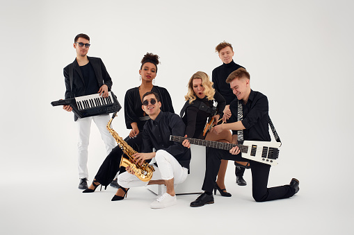 Portrait of diverse group of young people musical band playing with instruments - isolated on white background.