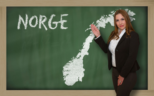 Successful, beautiful and confident young woman showing map of norway on blackboard for presentation, marketing research and tourist advertising