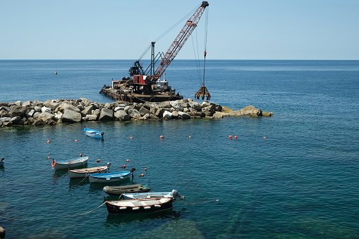 Riomaggiore, Cinque Terre, Liguria. About 6/2020. Barge with crane for dredging the seabed at the port of Riomaggiore, Cinque Terre, royalty free stock photo.