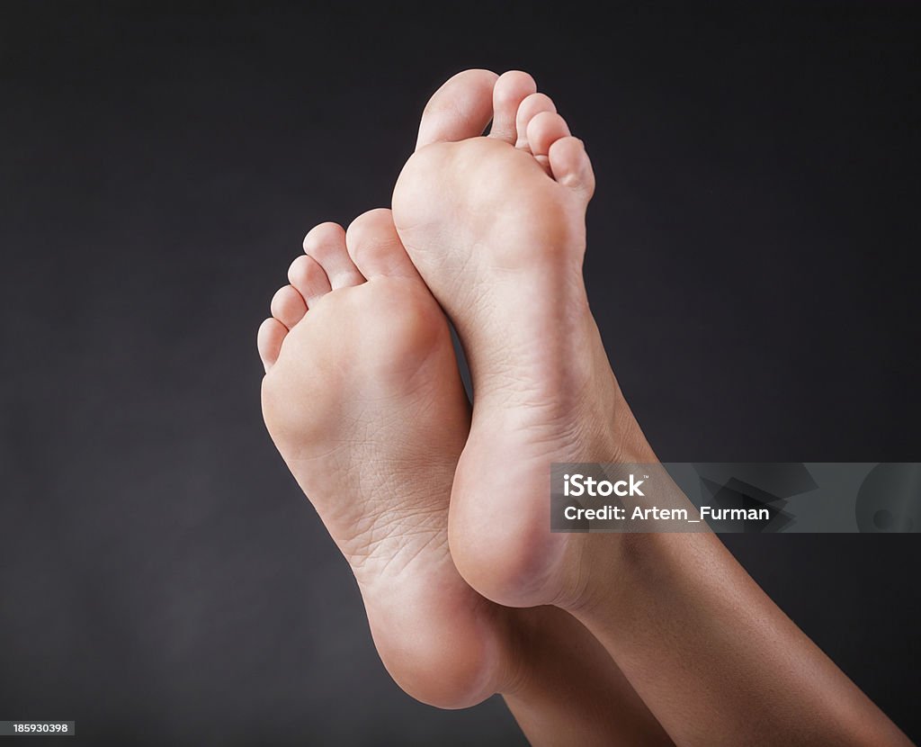 Women's heels Beautiful well-groomed female a foot and a heel on a black background Sole Of Foot Stock Photo