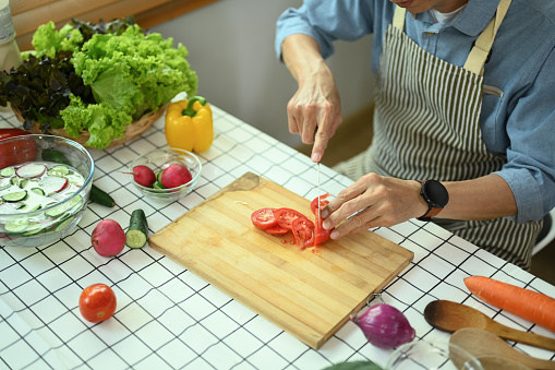 Cropped shot of senior man preparing ingredients for making healthy vegan salad in the kitchen