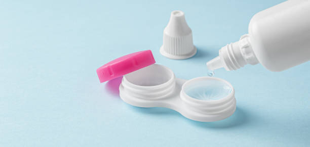 istock Pouring solution from bottle on contact lens in container on light blue background 1859326515