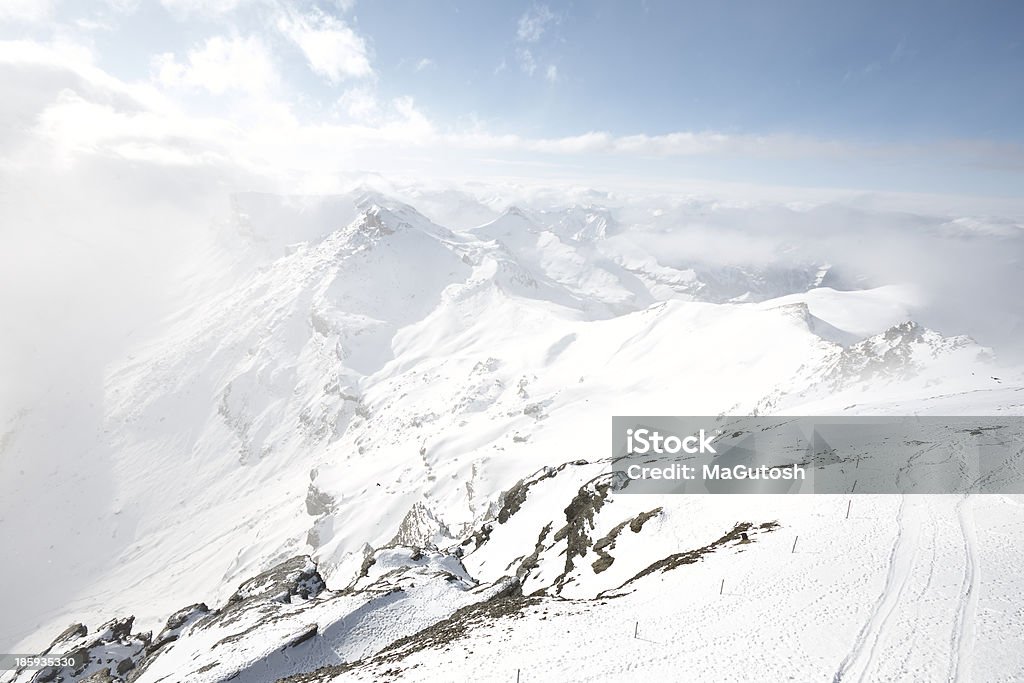 Snow covered mountain under thick cloud Clear view from the top with snow mountains of Swiss Alps, snowy mountains under thick cloud, with the edge of the Alps blended into the clouds. Aster Stock Photo