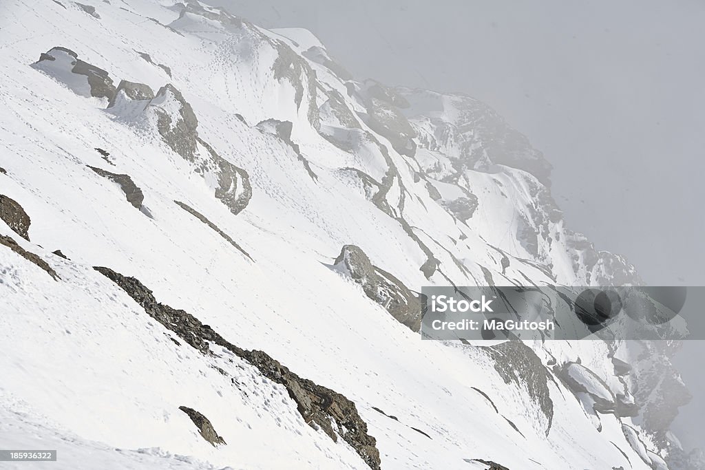 Mountain rocks coverd in snow Mountain rocks covered in thick snow, while strong wind blowing the snow across. Swiss Alps. Aster Stock Photo