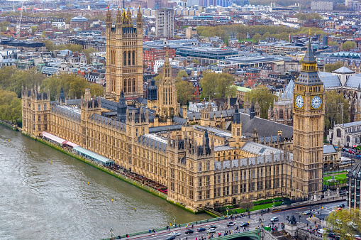 Aerial view along the busy street and traffic on Westminster Bridge, illuminated Big Ben and the Houses of Parliament. Motion Blured Car Lights. Twilight - Night Scene under vibrant skyscape. London City, United Kingdom, Europe