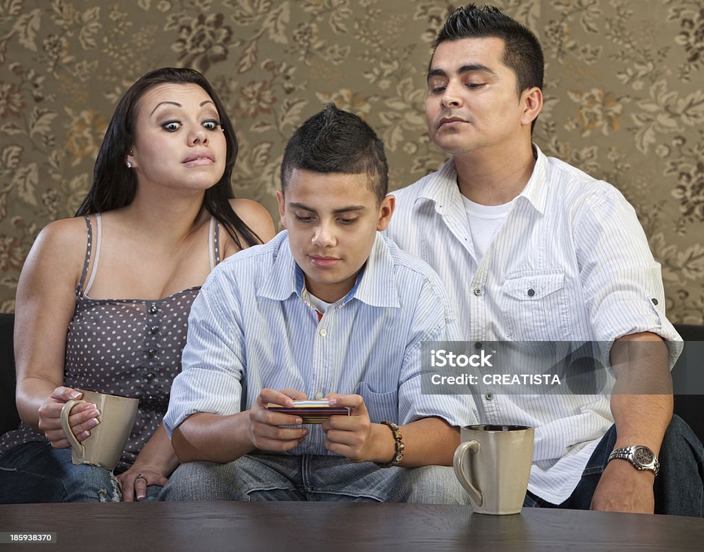 Genitori guardando adolescente, l'invio di messaggi - Foto stock royalty-free di Adolescente