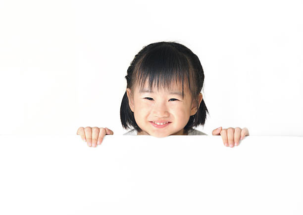 istock Asian little girl hiding behind white board 185938404