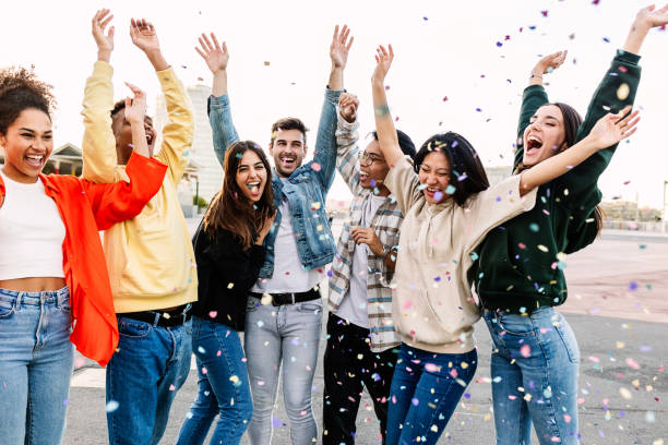 istock Young group of people enjoying outdoors party throwing confetti 1859394831