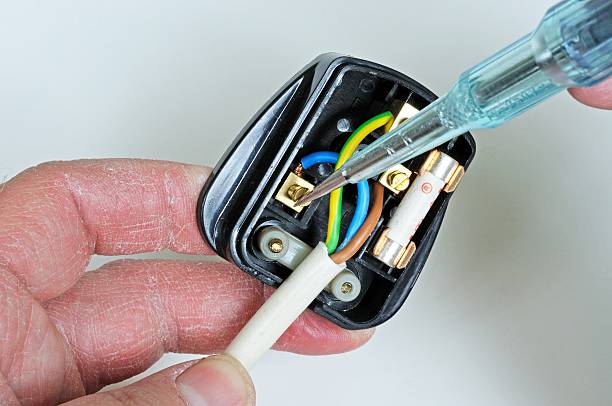 Wiring an English three pin plug. Man wiring English 3 pin 13 amp plug - inserting neutral wire, England, UK, Western Europe. three pin plug stock pictures, royalty-free photos & images