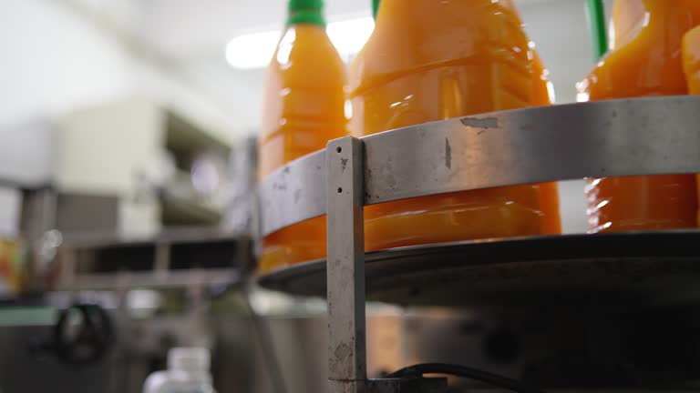 Production line of bottled juice beverage moving on conveyor belt in factory