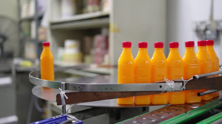 Production line of bottled juice beverage moving on conveyor belt in factory