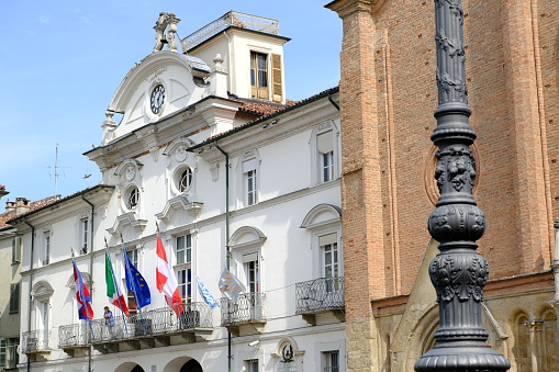 Asti, Italy. About 9-2021. Asti town hall.  Ancient Italian white palace with balcony and flags of Italy, Europe and Piedmont, waving in the wind.  Stock photos.
