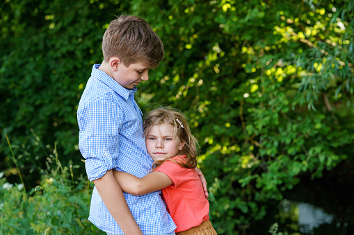 An upset little girl finds comfort in the embrace of her caring teenage brother, exemplifying the bond of a loving family. Loving Siblings, Brother and Sister