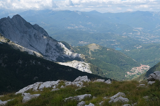 Mountains of the Apuan Alps between Monte Pisanino and Monte Cavallo. Mountains of the Apuan Alps between Monte Pisanino and Monte Cavallo. The Gramolazzo lake in the background. On the side of the Garfagnana delle Apuane there are numerous white marble quarries. The excavation is producing an environmental disaster as the mountains are destroyed to extract the marble. Foto stock royalty free. Alpi Apuane, Garfagnana, Italy.