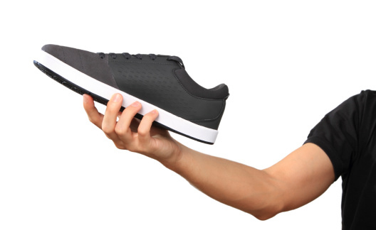 Human Hand with a new sport shoe / sneakers, isolated on white background. All logos and brand markings have been removed.